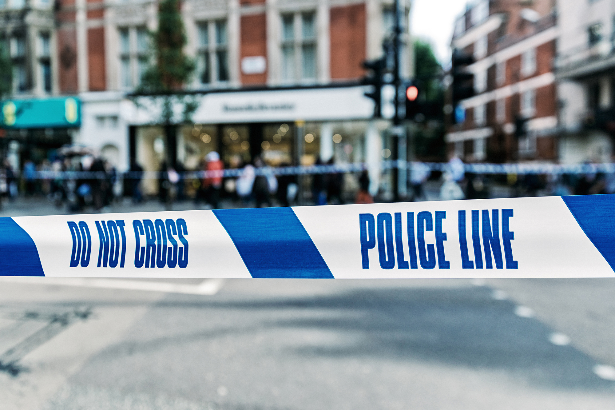 Police 'do not cross' tape on a busy highstreet