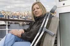 female sat in front of a harbour with crutches by her side