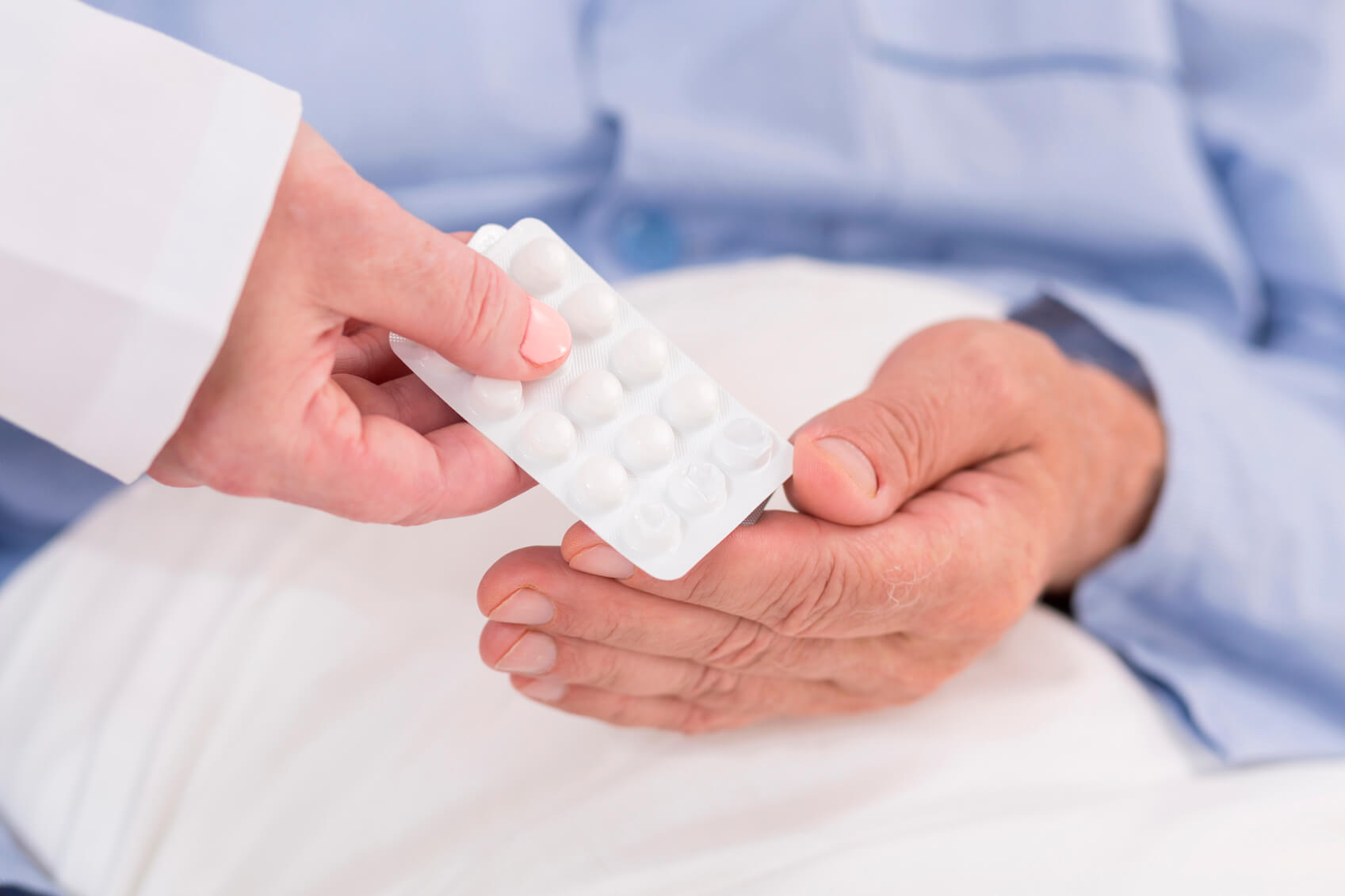 A doctor passing a packet of pills to a patient