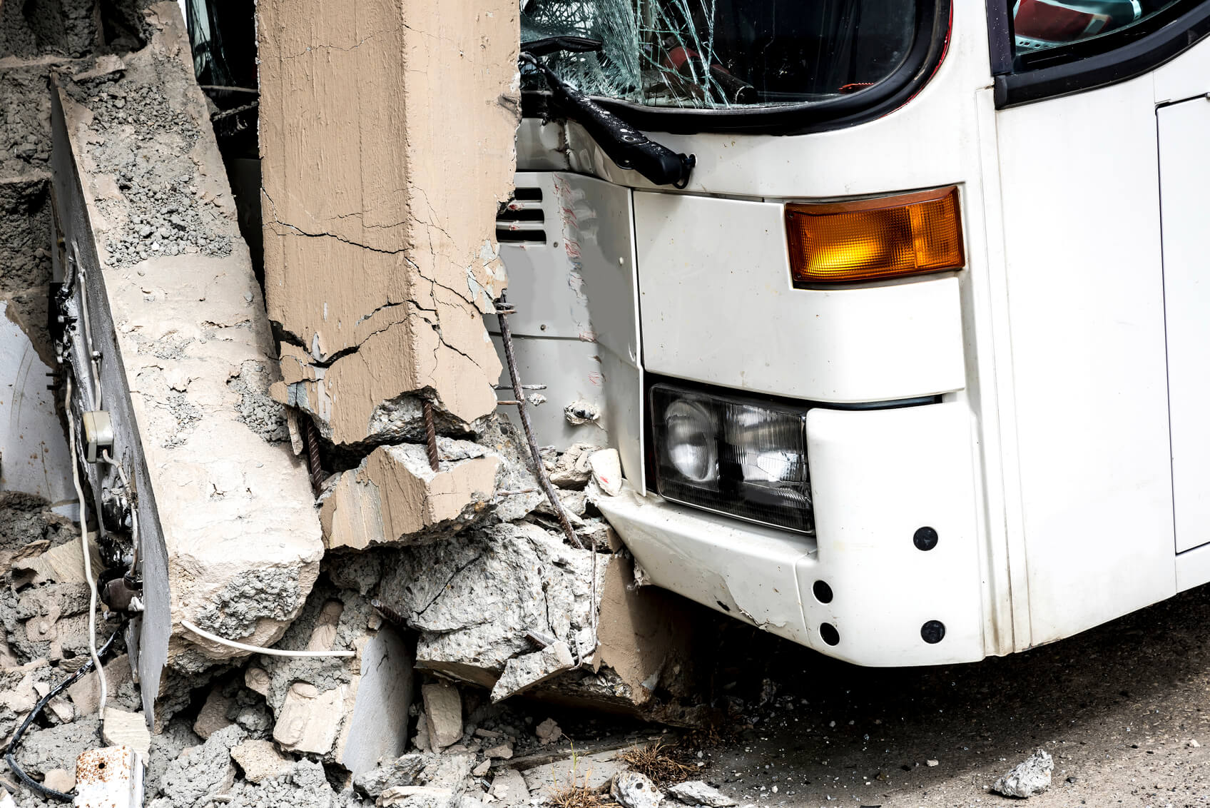 close up of a bus which has crashed into a wall both are damaged severely