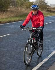 cyclist riding on the road wearing red jacket and blue helmet