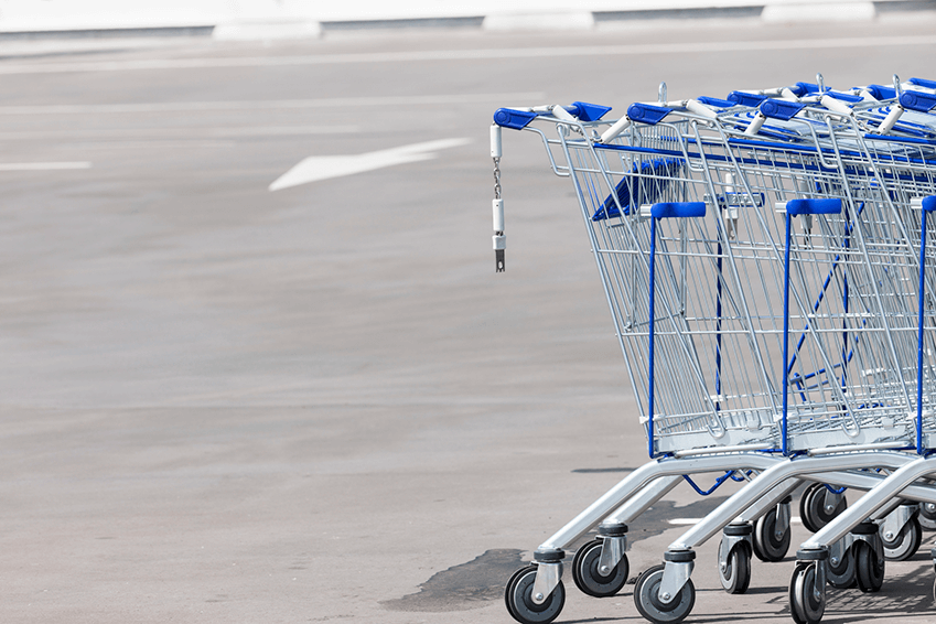 empty car park with a line of connected shopping trolleys right side of photo