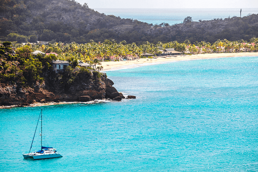 island with beach clear waters and a sailing boat