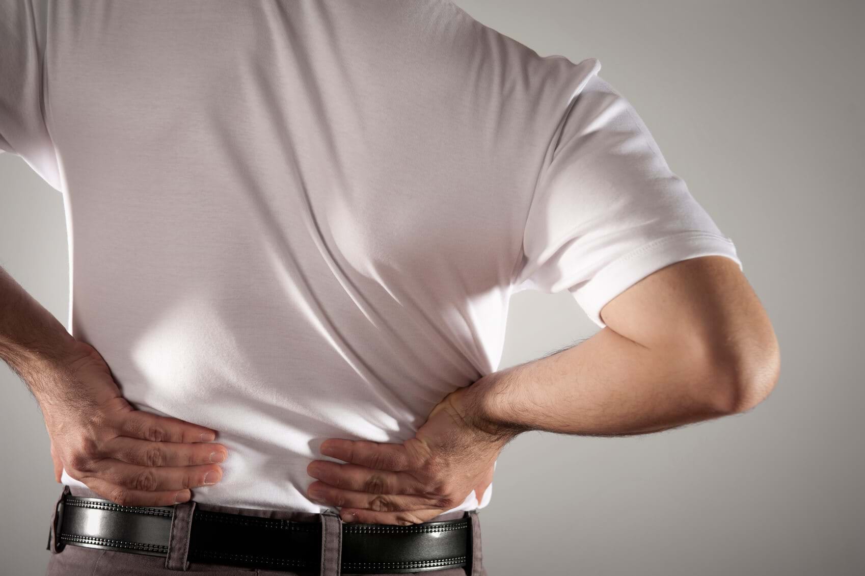 male in white t-shirt clutching his back in pain
