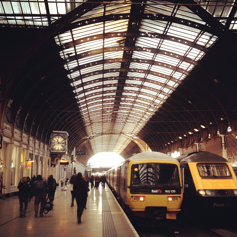front facing shot of two stationary trains at  a uk station with passengers on the platform