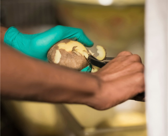 A close up of hands peeling a potato