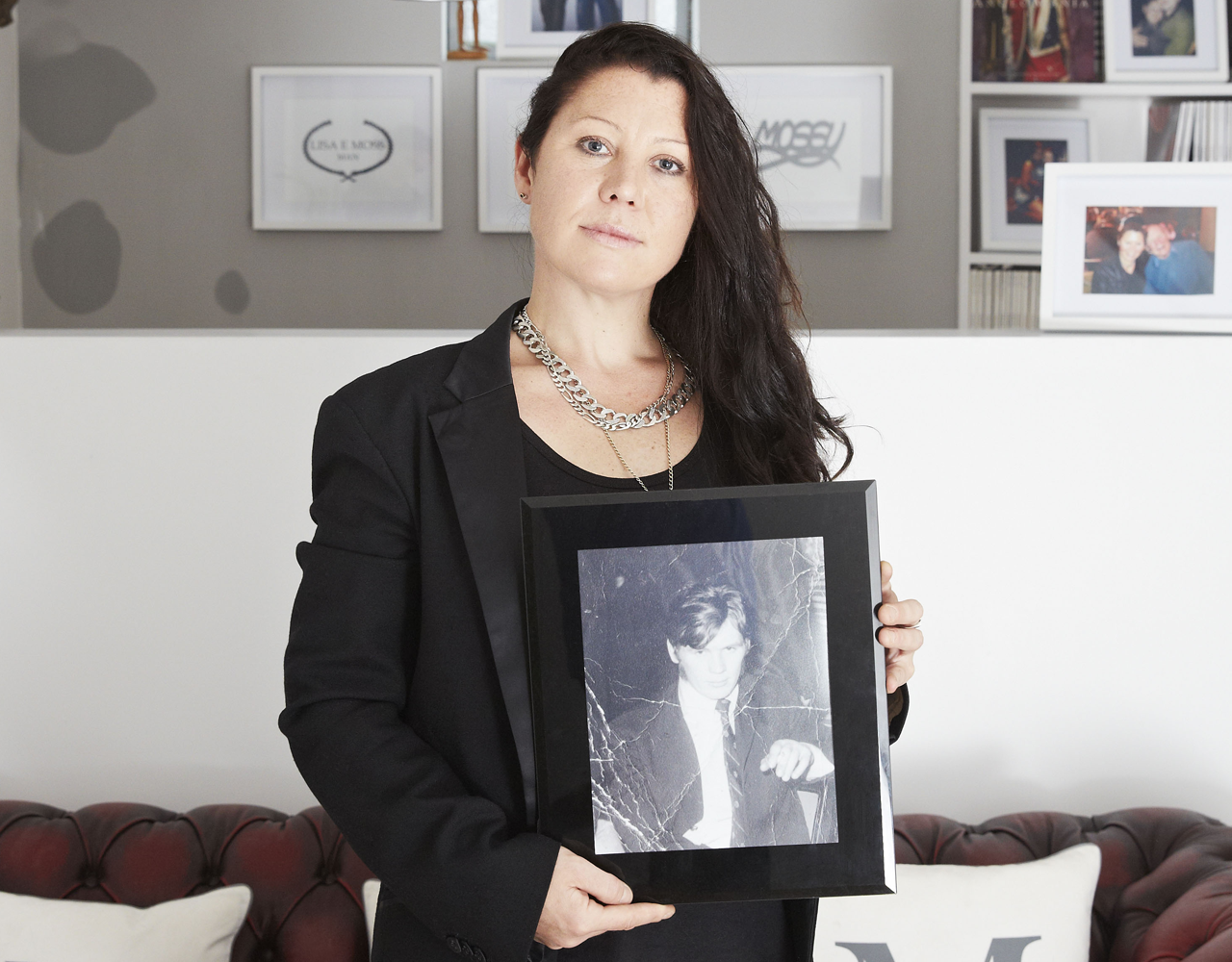 A lady in a smart dark jacket holds a framed photograph