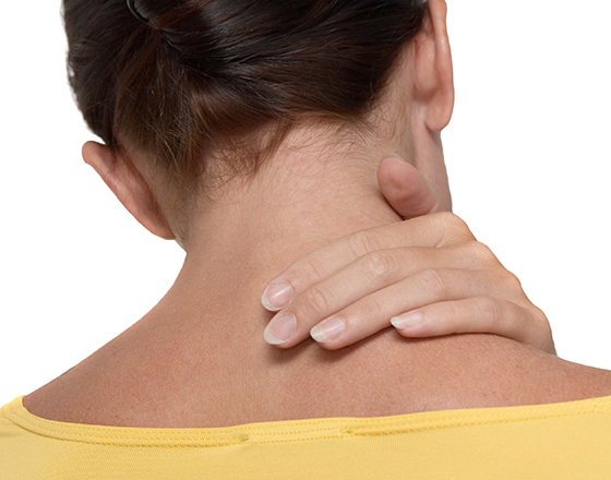 woman in yellow top stretching and touching her neck shot from behind