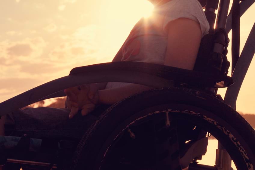sunset shot of a child's torso and legs sat in a wheelchair