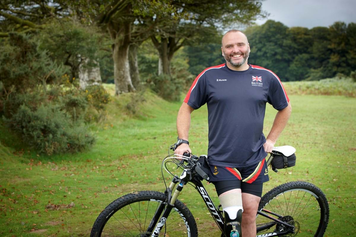 An image of Lee Spencer standing with his bicycle. 
