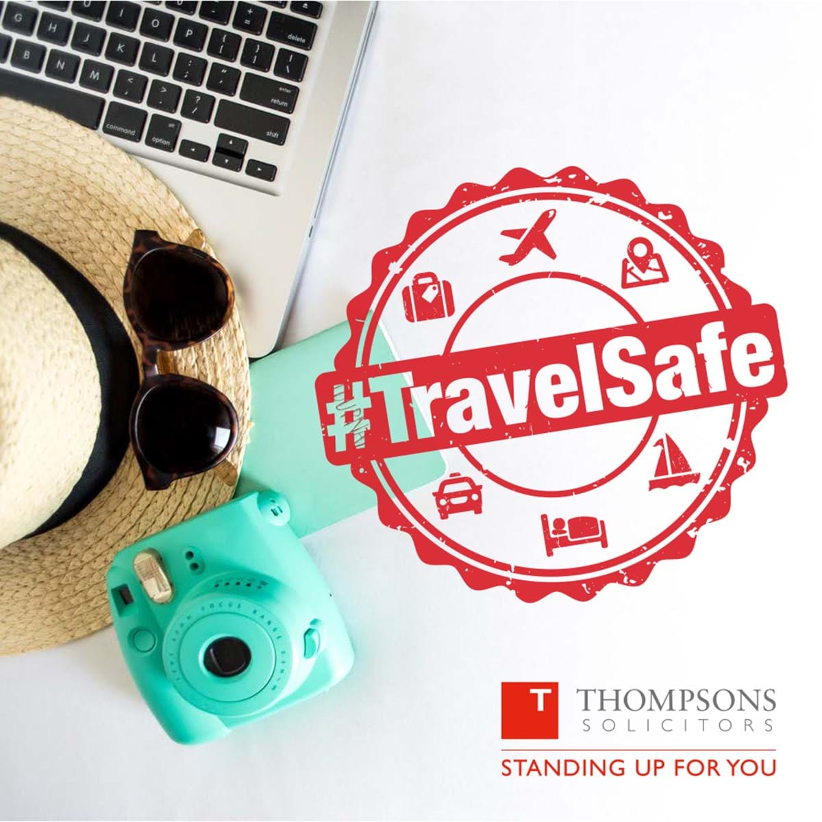 booking a package holiday on a laptop with camera, sunglasses, sunhat nearby