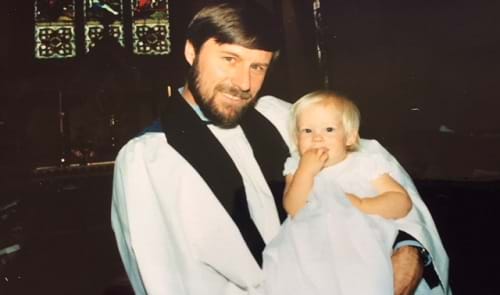 A vicar, Richard Bailey, holds a baby during a christening