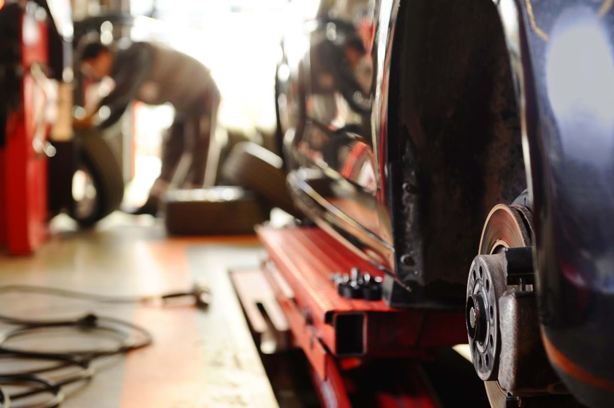 A car alloy up-close with a blurred silhouette of a mechanic in the background