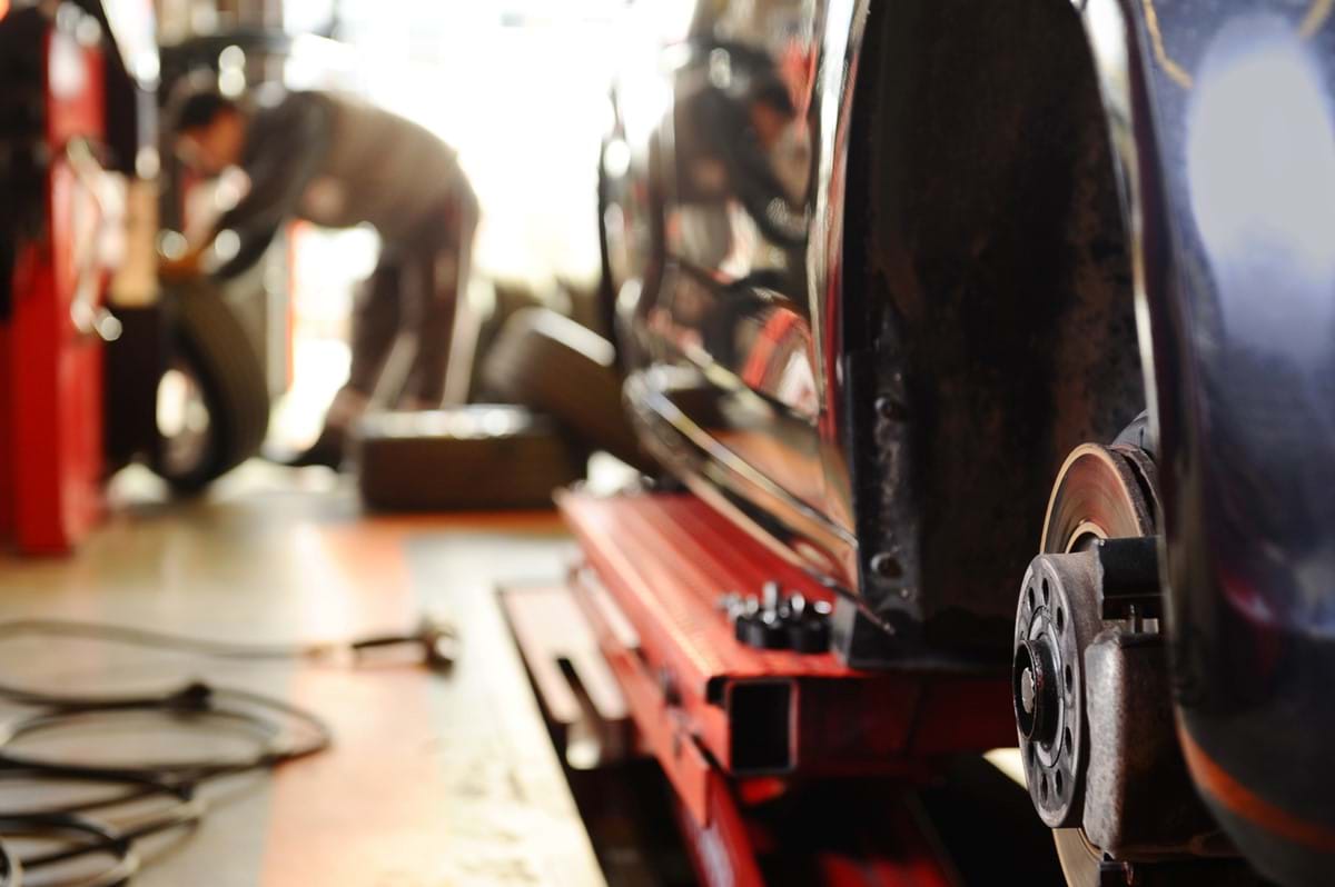 A car alloy up-close with a blurred silhouette of a mechanic in the background