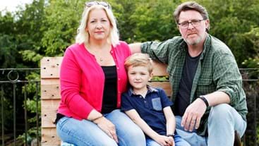 a man and woman sit on a bench with their son in the middle of them