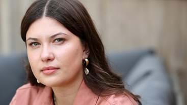 a young dark haired woman looks sternly at the camera