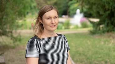 a lady stands in a park in a striped top