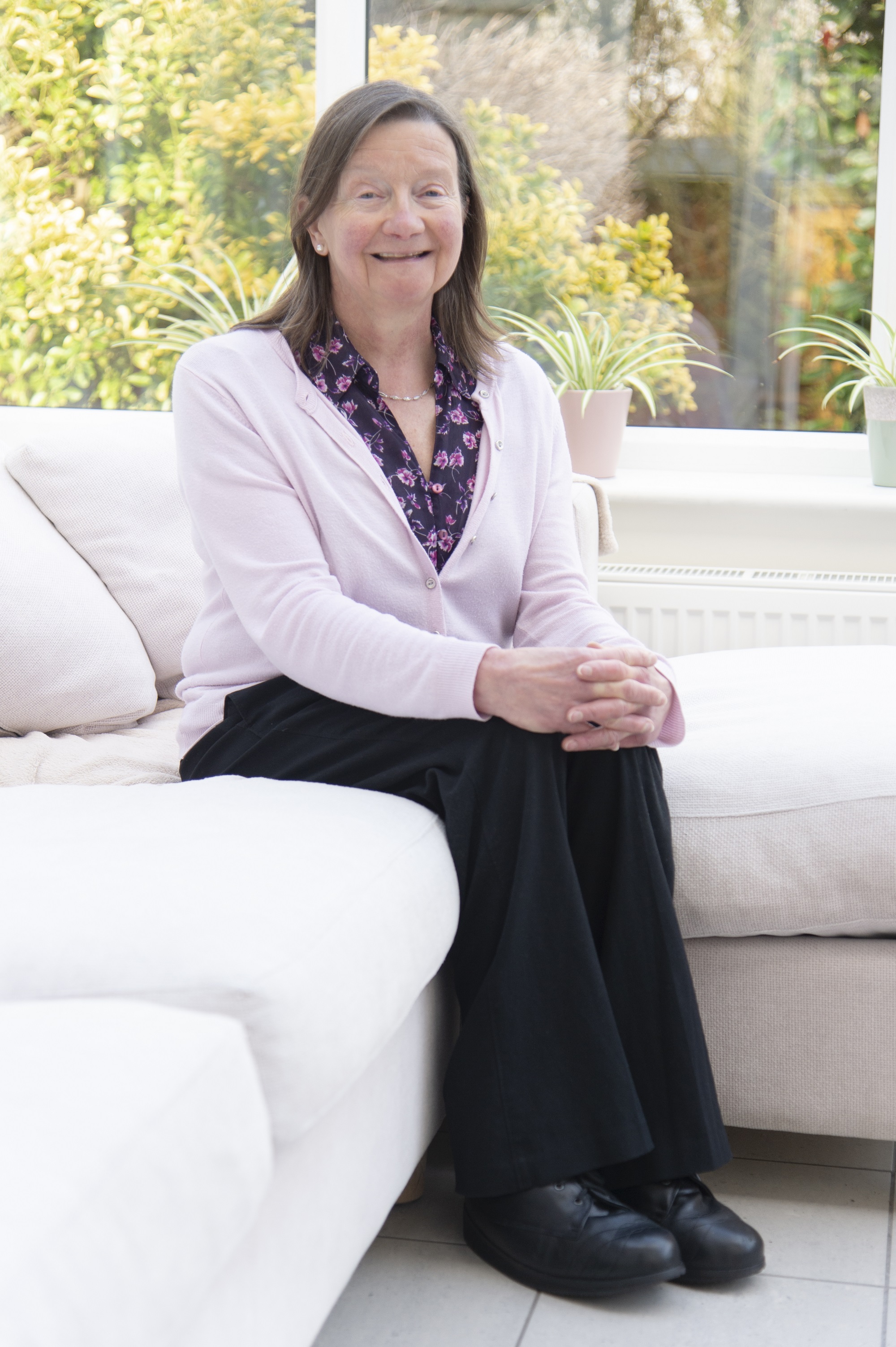 Judith Eva, sat down in her conservatory smiling at the camera