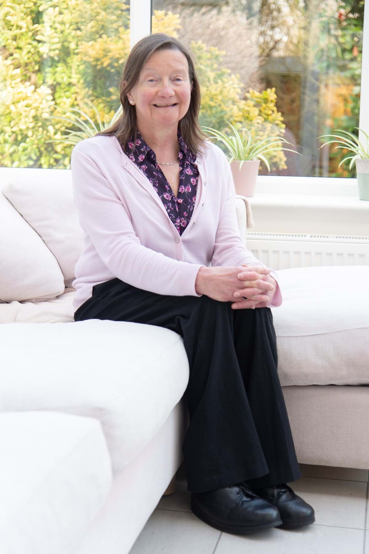 Judith Eva, sat down in her conservatory smiling at the camera