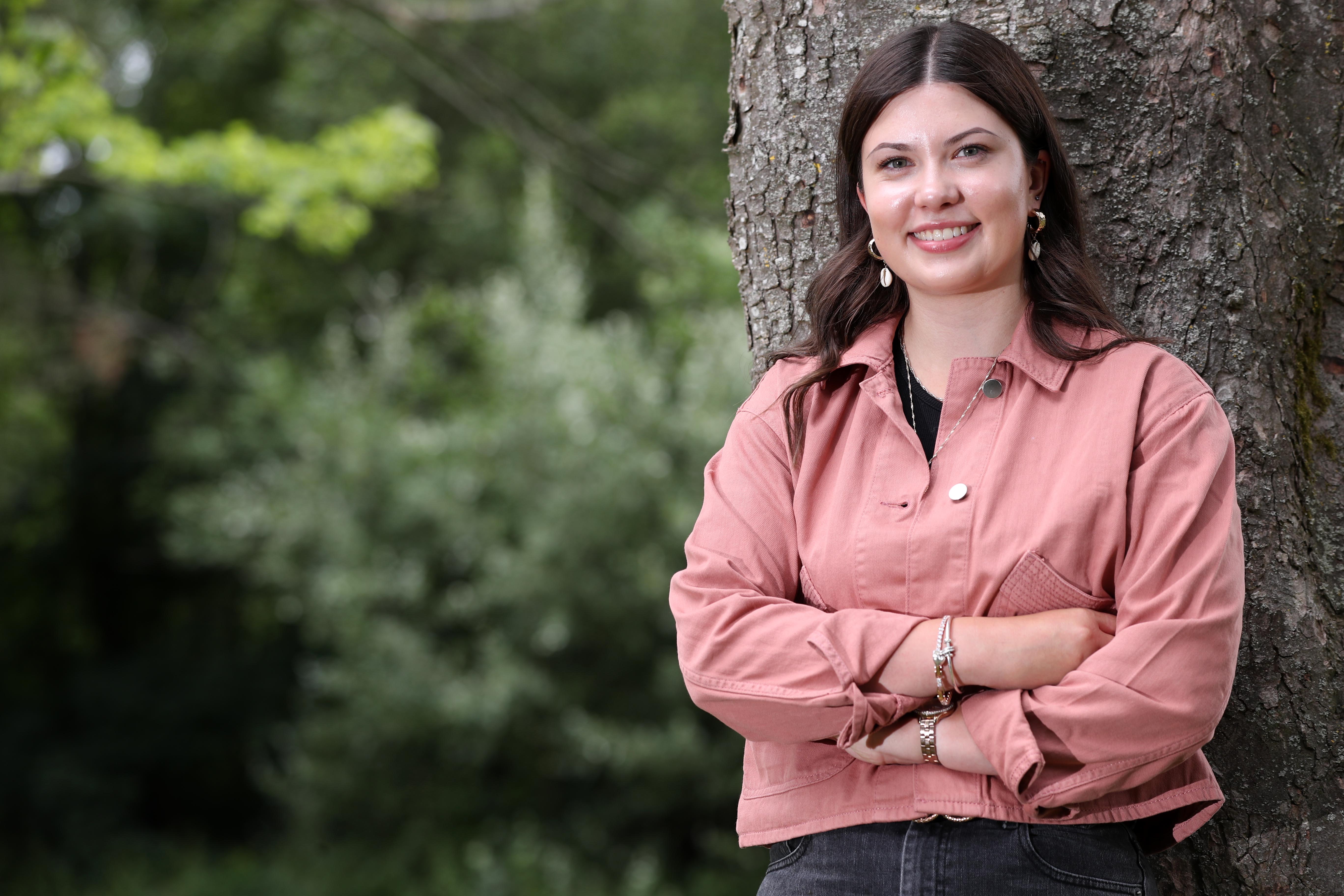 an image of a woman stood by a tree